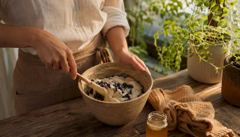 Hands mixing fresh blueberries into muffin batter