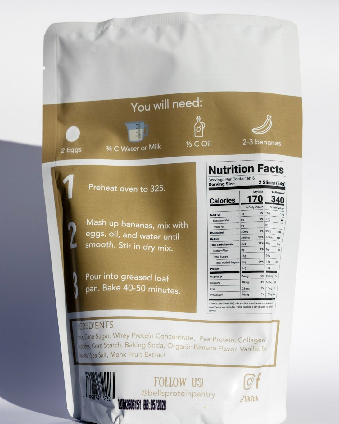 A stand-up pouch of banana smoothie mix shown from the back, featuring a white and tan design with a printed nutrition facts panel and preparation instructions, photographed on a light gray background with a soft shadow.